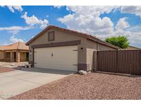 Single Gathering home featuring an attached garage with a two car driveway and low maintenance desert landscaping at 15633 W Acapulco Ln, Surprise, AZ 85379