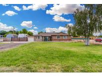 Charming single-story home with a well-manicured lawn, mature trees, and a welcoming facade under a bright sky at 25615 S Lemon Ave, Queen Creek, AZ 85142