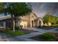 Charming single-Gathering home featuring a stone facade, two-car garage, and meticulously manicured landscaping at 2727 N Acacia Way, Buckeye, AZ 85396