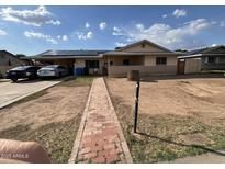 Modest home exterior with solar panels, brick pathway, and a covered carport at 6530 W Turney Ave, Phoenix, AZ 85033