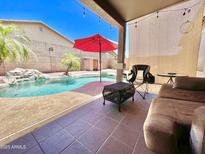 Inviting back patio with a red umbrella, pool, seating, and string lights for relaxing and entertaining at 723 S Weaver Dr, Apache Junction, AZ 85120