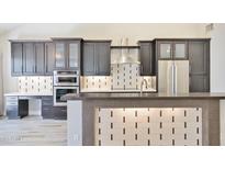 This kitchen features dark cabinets, stainless steel appliances, and a tile backsplash for a modern design at 7272 E Gainey Ranch Rd # 117, Scottsdale, AZ 85258