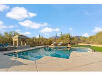 Inviting pool area featuring a stone fireplace, lounge chairs, umbrella, and desert landscaping at 4448 E Sleepy Ranch Rd, Cave Creek, AZ 85331