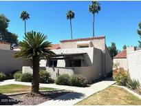 Inviting house featuring desert landscaping and palm trees against a clear blue sky at 7409 N Via Camello Del Norte -- # 138, Scottsdale, AZ 85258