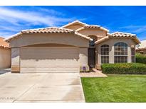 Charming single-story home with a tile roof, manicured lawn, and a two-car garage on a sunny day at 7930 W Wescott Dr, Glendale, AZ 85308