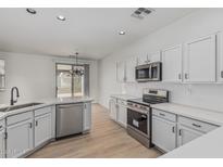 Modern kitchen with stainless steel appliances, sleek white cabinets, and light countertops at 1265 S Aaron -- # 271, Mesa, AZ 85209