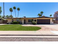 Inviting single-story home features a manicured lawn, palm trees, and a brick-paved driveway for a great curb appeal at 1535 E Kenwood St, Mesa, AZ 85203