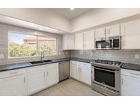 Bright kitchen featuring modern appliances, white cabinets, gray subway tile backsplash, and a window view at 26286 N 45Th Pl, Phoenix, AZ 85050