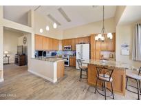Bright kitchen features wood cabinets, granite counters, tile backsplash, island and pendant lighting at 992 S Roanoke St, Gilbert, AZ 85296