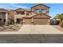 Two-story tan home featuring a three-car garage, tile roof, and low maintenance desert landscaping at 10758 E Lobo Ave, Mesa, AZ 85209