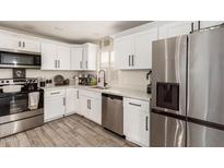 Well-lit kitchen featuring stainless steel appliances, white cabinets, and a stylish faucet at 11221 W Devonshire Ave, Phoenix, AZ 85037