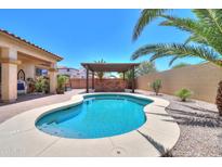 Inviting backyard oasis featuring a sparkling pool, spa, pergola, and lush desert landscaping at 1761 N Hester Trl, Casa Grande, AZ 85122