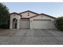 Charming single-story home featuring a two-car garage, landscaped yard, and a welcoming entrance with flags at 17825 W Lincoln St, Goodyear, AZ 85338