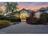 Stunning home exterior featuring a brick driveway, lush landscaping, and a warm, inviting entrance at dusk at 20644 E Sunrise Ct, Queen Creek, AZ 85142
