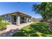 This backyard features a covered patio, green grass, an outdoor table and chairs, and some small trees at 23179 S 225Th Pl, Queen Creek, AZ 85142