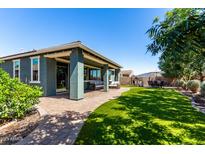 Inviting covered patio with stylish seating overlooks the lush green lawn and landscaped backyard at 23179 S 225Th Pl, Queen Creek, AZ 85142