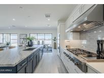 Bright open kitchen with white cabinets, stainless steel appliances, and an island with marble countertop at 24000 S 218Th Pl, Queen Creek, AZ 85142