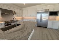 Gourmet kitchen featuring sleek white cabinets, stainless steel appliances, an island and stunning stone countertops at 24000 S 218Th Pl, Queen Creek, AZ 85142