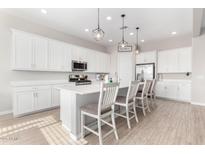 Modern kitchen with white cabinetry, a center island with seating, and stainless steel appliances at 32582 N Durango Ln, San Tan Valley, AZ 85143