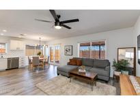 Bright and airy living room with gray sectional sofa, wood coffee table and decor, and dining area, all under a modern ceiling fan at 343 S Cholla St, Gilbert, AZ 85233