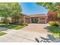 Beautiful single-story home featuring a paver driveway, a two-car garage, stone accents and mature landscaping at 4141 E Morrison Ranch Pkwy, Gilbert, AZ 85296