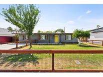 Charming home with a well-manicured lawn, wooden fence, and eye-catching yellow front door at 6814 N 14Th St, Phoenix, AZ 85014