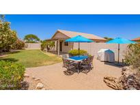 Inviting backyard with patio dining set, lush landscaping, and covered porch at 13824 N 148Th Ln, Surprise, AZ 85379