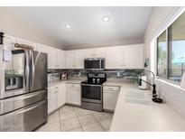 Well-lit kitchen features stainless steel appliances, white cabinets, and a modern sink at 13824 N 148Th Ln, Surprise, AZ 85379