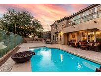 Gorgeous backyard with a sparkling pool, stone patio, outdoor fireplace, and covered seating area at 921 E Canyon Way, Chandler, AZ 85249