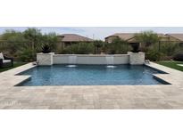 Backyard swimming pool featuring a tiled waterfall feature and travertine tile decking at 24035 N 171St Dr, Surprise, AZ 85387
