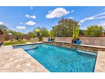 Backyard oasis featuring a sparkling pool with stone accents and lush desert landscaping at 2604 W Balao Dr, Phoenix, AZ 85085