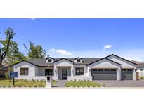 Charming single-story home boasts a white brick facade, gray roof, and meticulously manicured lawn at 4456 E Earll Dr, Phoenix, AZ 85018