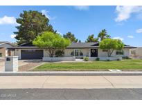 Charming single-story home with manicured lawn, mature trees, and a brick facade at 401 E Braeburn Dr, Phoenix, AZ 85022