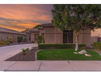 Charming home featuring lush landscaping, verdant lawn, a stone accent wall, and a circular driveway at 712 W Jade Dr, Chandler, AZ 85248