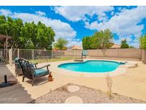 Inviting backyard pool with stone patio, lush greenery, and comfortable seating, perfect for relaxation and entertainment at 10566 E Bogart Ave, Mesa, AZ 85208