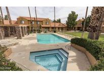 Exterior shot of pool and hot tub, surrounded by landscaped grounds and multi-story condo complex in the background at 3511 E Baseline Rd # 1235, Phoenix, AZ 85042