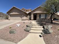 A charming house with a beige exterior, a two-car garage, mature landscaping, and a stone walkway at 4016 E Western Star Blvd, Phoenix, AZ 85044