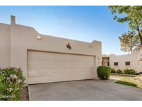 Neutral garage door with bronco art matches the home's southwestern aesthetic in front of manicured landscaping at 5445 E Mckellips Rd # 23, Mesa, AZ 85215