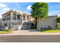Beautiful two-story home featuring a three-car garage and a well-manicured front yard with a large tree at 8429 E Del Camino Dr, Scottsdale, AZ 85258