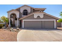 Two-story home with a gray exterior, a tiled roof, and a three-car garage showcasing its attractive curb appeal at 9203 E Topeka Dr, Scottsdale, AZ 85255
