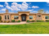 Charming home exterior showcasing beautiful stonework, lush green lawn, and an inviting front entrance at 13206 N 64Th St, Scottsdale, AZ 85254