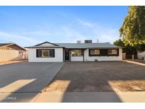 Charming single-story home featuring a fresh white exterior, contrasting black trim, and large front yard at 13624 N 31St Ave, Phoenix, AZ 85029