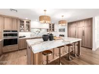 Bright kitchen features a marble waterfall island, stainless steel appliances, and custom wood cabinetry at 16227 N 63Rd Pl, Scottsdale, AZ 85254