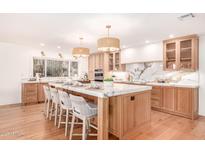 Bright kitchen features a large island with marble countertop and seating, complemented by wooden cabinets and modern appliances at 16227 N 63Rd Pl, Scottsdale, AZ 85254