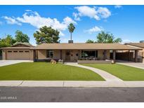Charming single-story home with a well-manicured lawn, welcoming walkway, and palm tree under a partly cloudy sky at 1640 E Solano Dr, Phoenix, AZ 85016