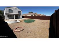 Wide backyard with a putting green, patio, gravel area, fire pit, and a fence surrounding the property at 37061 W Bello Ln, Maricopa, AZ 85138