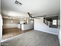 Bright living room has a ceiling fan and overlooks the kitchen and staircase at 37061 W Bello Ln, Maricopa, AZ 85138