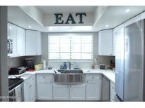 Modern kitchen with white cabinets, stainless steel appliances, and a farmhouse sink at 6885 E Cochise Rd # 127, Paradise Valley, AZ 85253