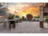 Inviting backyard featuring a built-in grill, fire pit, and ample seating under a beautiful sunset sky at 13583 S 177Th Ln, Goodyear, AZ 85338