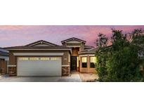 Inviting home exterior with a two-car garage, tidy landscape, and warm lighting at 16763 W Magnolia St, Goodyear, AZ 85338